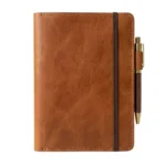 Cognac brown full-grain leather journal cover with brass pen holder and elastic strap on white background - Rove Leather
