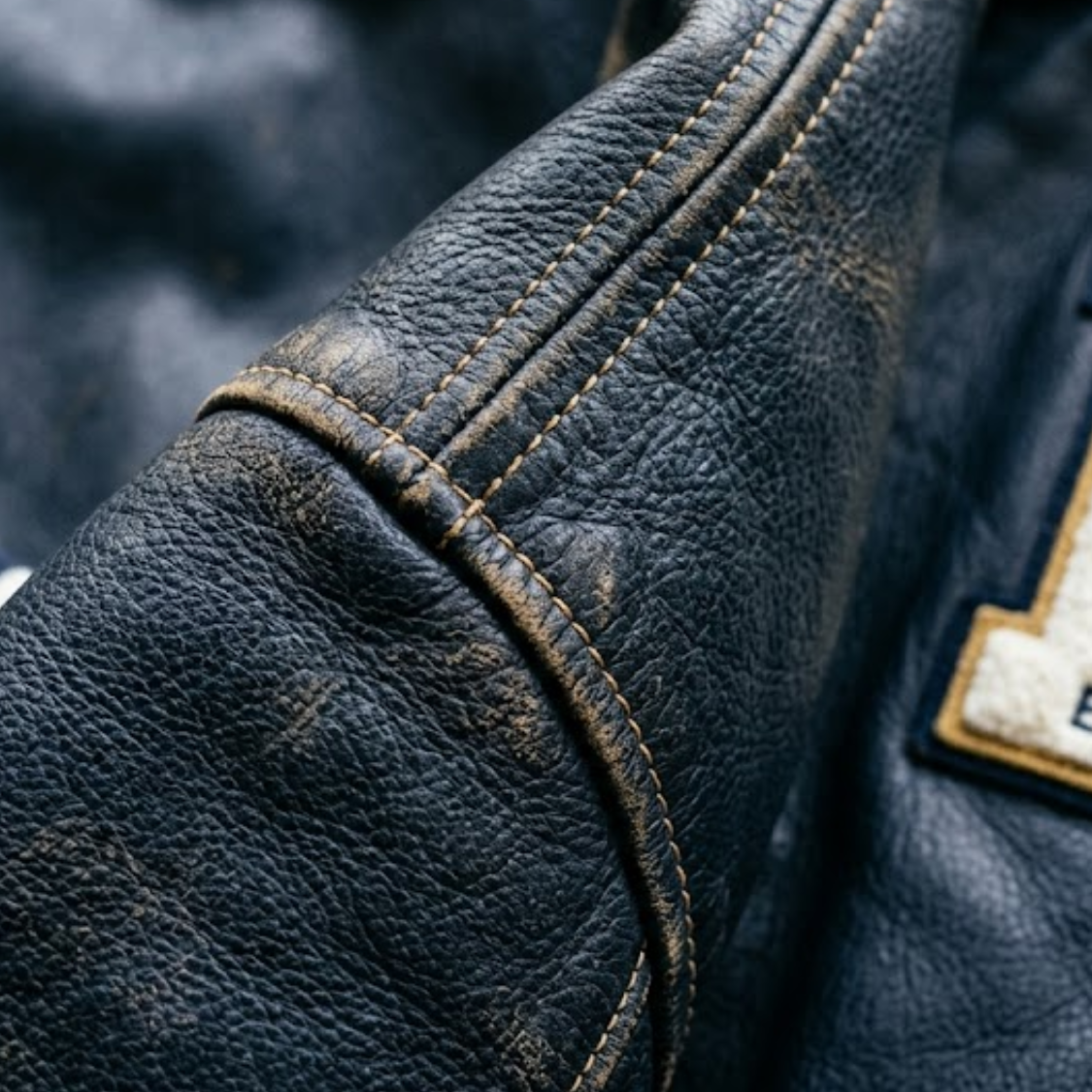 Close up of the shoulder seam where a leather sleeve meets the jacket body