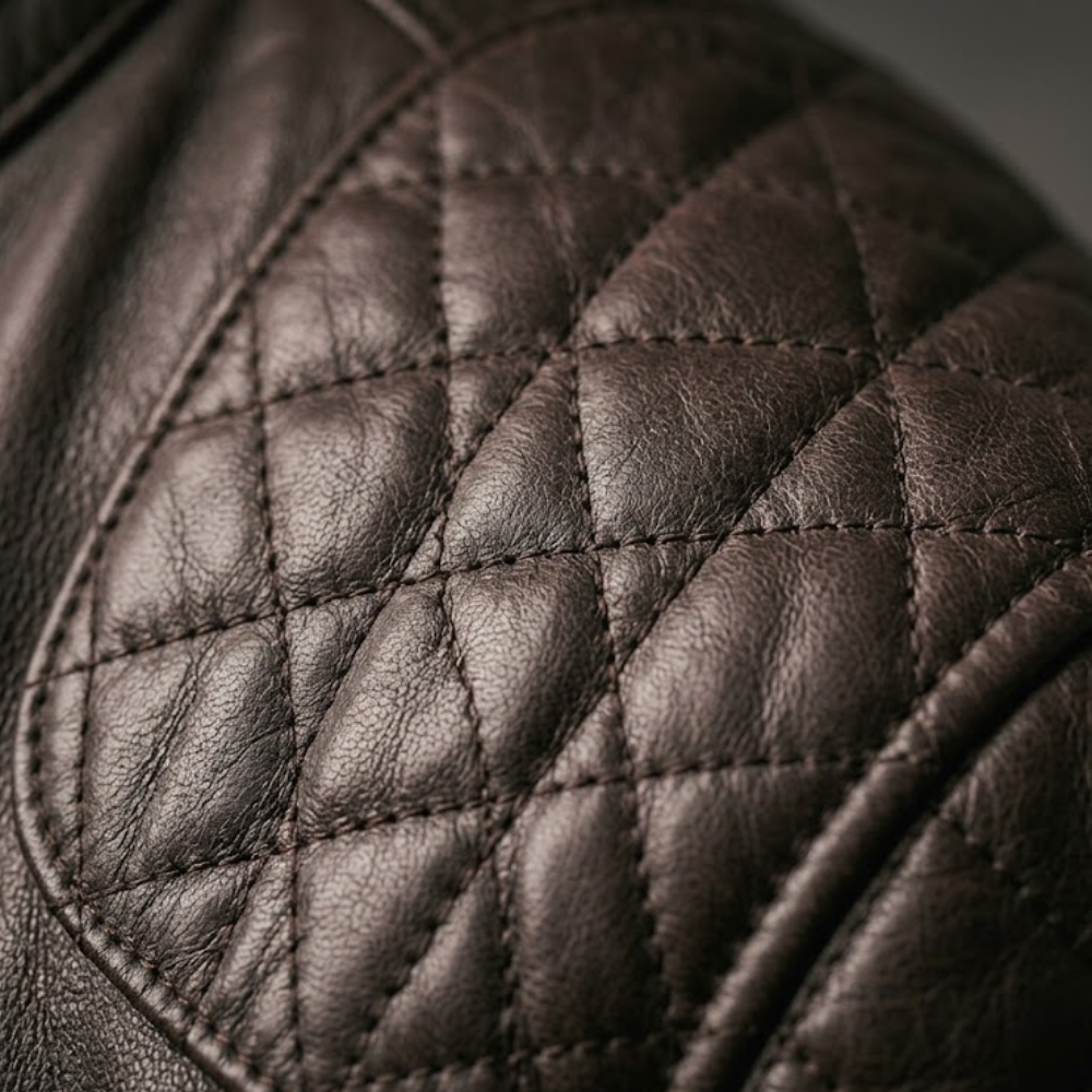 Close up of diamond quilted shoulder panel on a dark brown leather cafe racer jacket